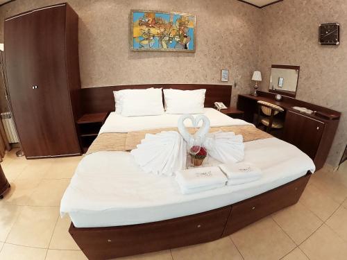 a hotel room with a bed with two swans on it at Family Resort Hotel Милоо in Loo