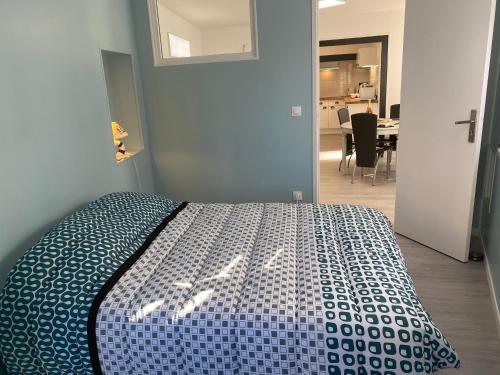 a bedroom with a bed with a blue and white comforter at L’Abri Côtier in Le Tréport