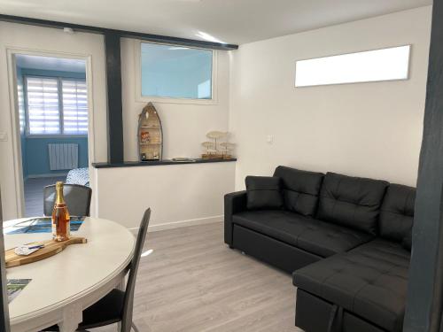 a living room with a black couch and a table at L’Abri Côtier in Le Tréport