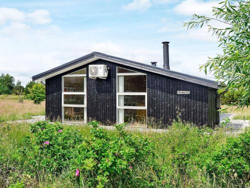 a black building with a chimney on top of a field at 6 person holiday home in Fan in Sønderho