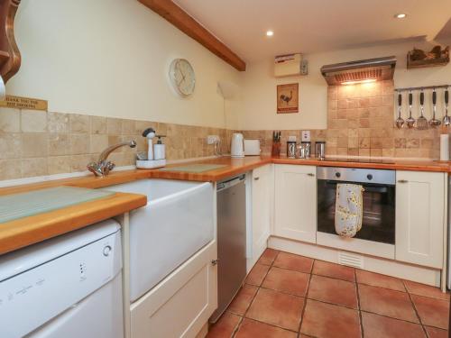 a kitchen with white cabinets and a tile floor at The Old Stables in Ross on Wye