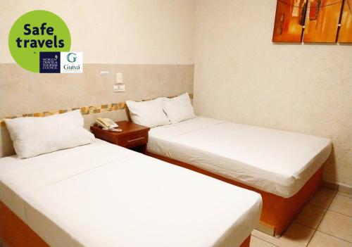 - 2 lits dans une chambre d'hôtel avec un panneau indiquant que vous voyagez en toute sécurité dans l'établissement Hotel Guivá Huatulco, à Santa Cruz Huatulco