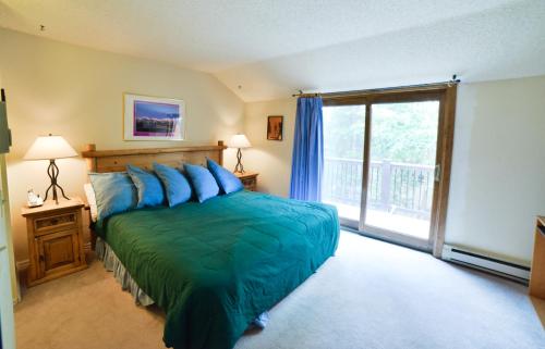 a bedroom with a green bed and a balcony at 200_Primrose in Breckenridge