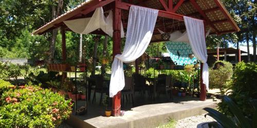 a gazebo with tables and chairs in a garden at Anda Poseidon’s Beach Resort in Anda