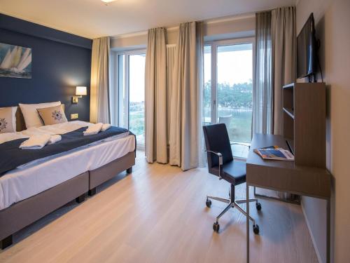 1 dormitorio con cama, escritorio y silla en Dünenresidenz Prora - Ferienwohnung mit Meerblick, 3 Schlafzimmern und Balkon NP-406, en Binz