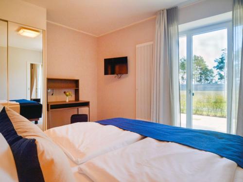 ein Schlafzimmer mit einem Bett und einer Glasschiebetür in der Unterkunft Dünenresidenz Prora - Ferienwohnung mit Meerblick und 1 Schlafzimmer und Terrasse NP-704 in Binz