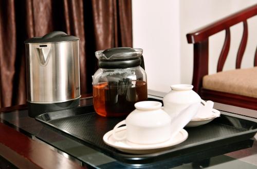 Puthens Capitol Inn في إرناكولام: طاولة عليها صانع قهوة واواني الشاي