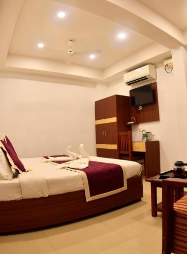 a hotel room with a bed and a kitchen at Puthens Capitol Inn in Ernakulam