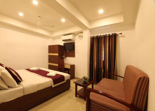 a hotel room with a bed and a chair at Puthens Capitol Inn in Ernakulam