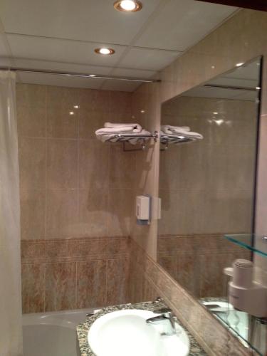 a bathroom with a sink and a mirror and a tub at Hotel Xalet Verdú in Arinsal