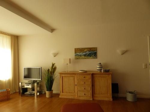 ヴィーク・アウフ・フェールにあるHaus Halligblick Whg 20のリビングルーム(テレビ、木製ドレッサー付)