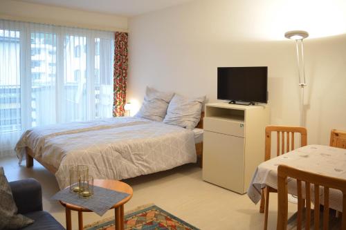 1 dormitorio con 1 cama, TV y mesa en Willkommen-Gemütlich, Balkon, Parkplatz direkt in St Moritz, en St. Moritz