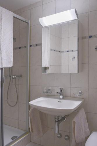 a white bathroom with a sink and a shower at Willkommen-Gemütlich, Balkon, Parkplatz direkt in St Moritz in St. Moritz