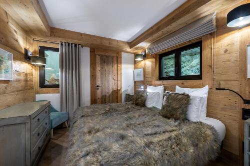 une chambre avec un grand lit et des murs en bois dans l'établissement Penthouse Best View - Les Chalets COVAREL, à Val dʼIsère