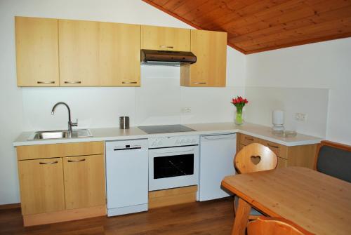 cocina con electrodomésticos blancos y mesa de madera en Filzmoos Appartements, en Filzmoos