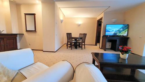 un soggiorno con un divano, un tavolo e una televisione di Apartament 2706 Alpin Resort, etaj 7, Poiana Brașov a Poiana Brasov