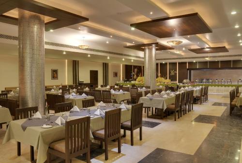 a dining room with tables and chairs in a building at Inder Residency Resort & Spa Udaipur in Udaipur