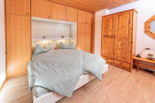 Imberg-Suite mit Schwimmbad في اوبرستوفن: غرفة نوم بسرير كبير وخزانة خشبية