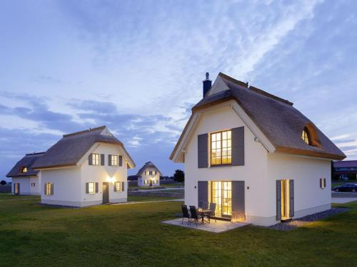 a large white house with a black roof at Reetland am Meer - Superior Reetdachvilla mit 2 Schlafzimmern E02 in Dranske