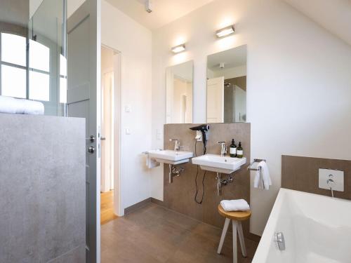 a bathroom with two sinks and two mirrors at Reetland am Meer - Premium Reetdachvilla mit 2 Schlafzimmern, Sauna und Kamin E13 in Dranske