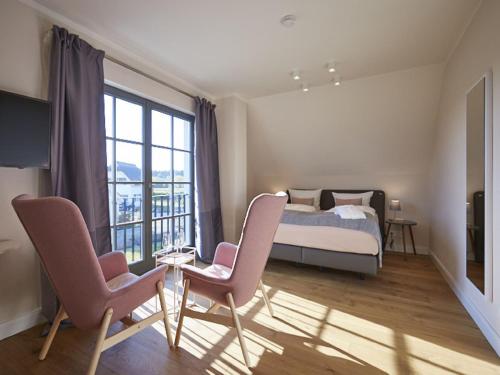 德蘭斯克的住宿－Reetland am Meer - Premium Reetdachvilla mit 3 Schlafzimmern, Sauna und Kamin E16，一间卧室配有一张床、两把椅子和一个窗户