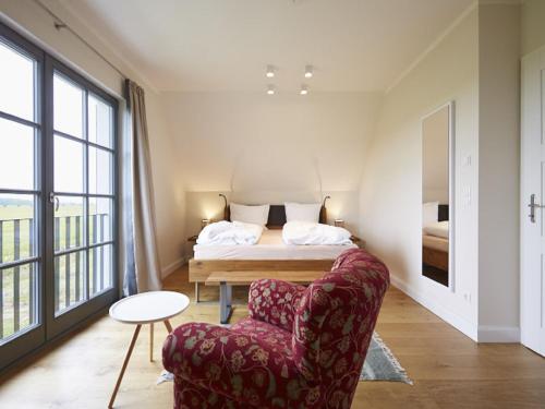 um quarto com uma cama, uma cadeira e um sofá em Reetland am Meer - Premium Reetdachvilla mit 3 Schlafzimmern, Sauna und Kamin E19 em Dranske