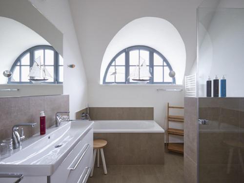 a bathroom with two arched windows and a bath tub at Reetland am Meer - Premium Reetdachvilla mit 3 Schlafzimmern, Sauna und Kamin E19 in Dranske