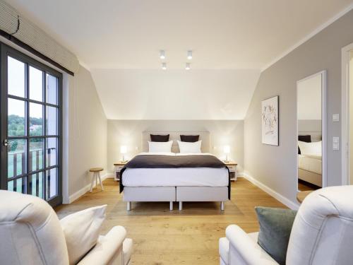 1 dormitorio con 1 cama y 2 sillas blancas en Reetland am Meer - Superior Reetdachvilla mit 2 Schlafzimmern E14, en Dranske