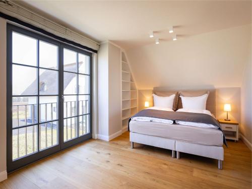 1 dormitorio con cama y ventana grande en Reetland am Meer - Premium Reetdachvilla mit 3 Schlafzimmern, Sauna und Kamin E08, en Dranske