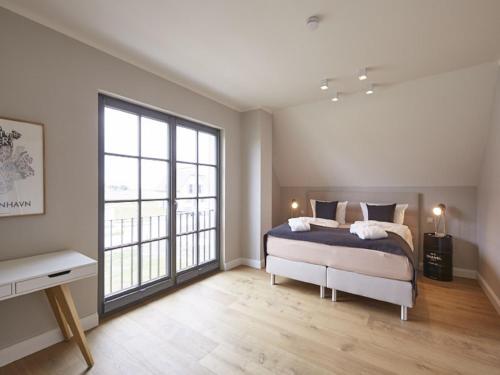 a bedroom with a bed and a large window at Reetland am Meer - Premium Reetdachvilla mit 3 Schlafzimmern, Sauna und Kamin E24 in Dranske