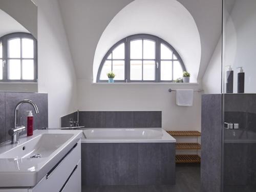 a bathroom with a sink and a bath tub at Reetland am Meer - Premium Reetdachvilla mit 3 Schlafzimmern, Sauna und Kamin E21 in Dranske