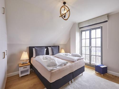 Un dormitorio con una cama grande y una ventana en Reetland am Meer - Luxus Reetdachvilla mit 3 Schlafzimmern, Sauna und Kamin E27, en Dranske