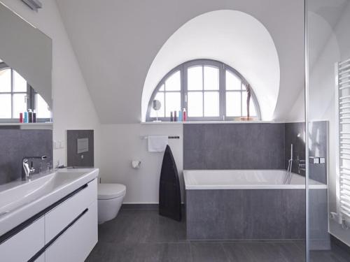 uma casa de banho com uma banheira, um lavatório e um WC. em Reetland am Meer - Luxus Reetdachvilla mit 3 Schlafzimmern, Sauna und Kamin E27 em Dranske