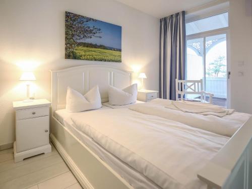 a white bedroom with a white bed and a window at Strandvillen Binz - Ferienwohnung mit Meerblick, 2 Schlafzimmern und Balkon SV-008 in Binz