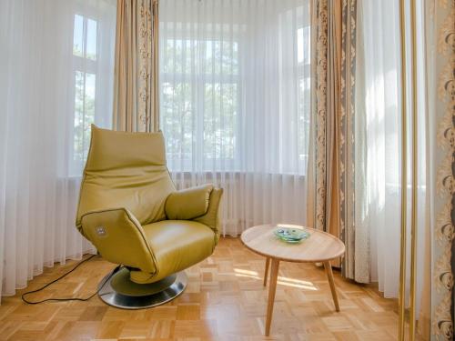 een woonkamer met een groene stoel en een tafel bij Strandvillen Binz - Ferienwohnung mit Meerblick und 1 Schlafzimmer SV-710 in Binz