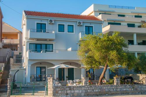 a white building with a tree in front of it at Beach Apartments in Tivat