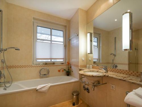 een badkamer met een bad, een douche en een wastafel bij Kaiservillen Heringsdorf - Ferienwohnung mit 1 Schlafzimmer und Balkon C23 in Heringsdorf