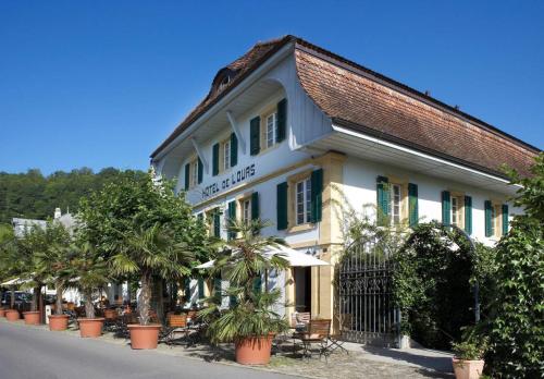 a building with palm trees in front of a street at Romantik Hotel de L'Ours in Sugiez