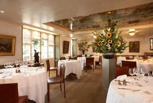 a dining room with white tables and a large vase of flowers at Romantik Hotel de L'Ours in Sugiez