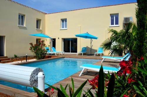 - une piscine avec des chaises et des parasols à côté d'un bâtiment dans l'établissement Résidence L'art Doise, à Rochefort
