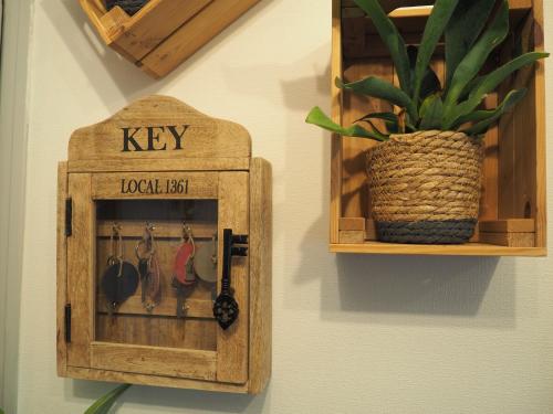 a wooden key hanging on a wall with a potted plant at Logis Hôtel Vannes Nord Le Clos Des Hortensias in Locqueltas