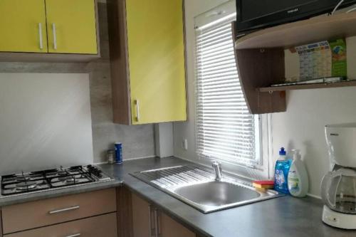 una cocina con fregadero y estufa en Mobil-Home 6 personnes à Munster en Alsace, en Munster