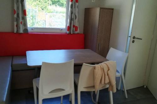 cocina con mesa y 2 sillas blancas en Mobil-Home 6 personnes à Munster en Alsace, en Munster