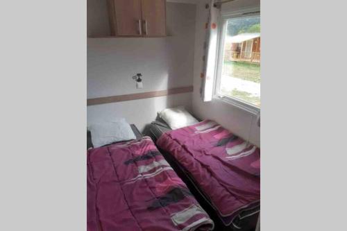 Cette chambre comprend deux lits installés à côté d'une fenêtre. dans l'établissement Mobil-Home 6 personnes à Munster en Alsace, à Munster