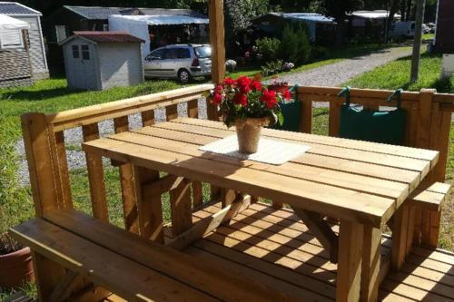 a wooden picnic table with a vase of flowers on it at Mobil-Home 6 personnes à Munster en Alsace in Munster