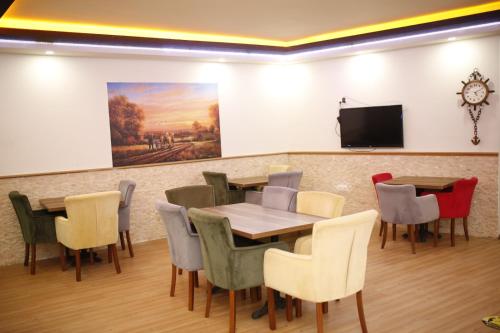 uma sala de jantar com mesa e cadeiras e uma televisão de ecrã plano em Özhan Hotel em Antália