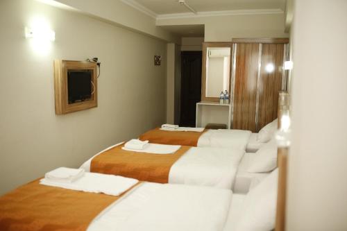 a hotel room with three beds and a mirror at Özhan Hotel in Antalya