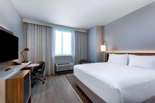 a hotel room with a bed and a desk and a television at Wyndham Garden Miami International Airport in Miami