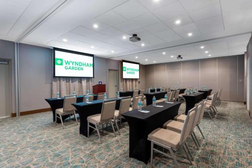 a conference room with tables and chairs and a screen at Wyndham Garden Miami International Airport in Miami