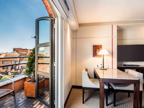 a room with a table and a balcony with a view at Sofitel Bogota Victoria Regia in Bogotá